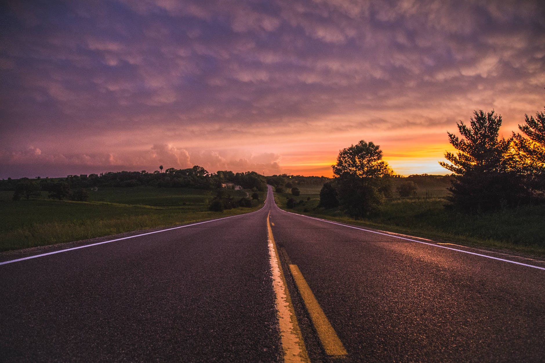 Photo of empty road in between grass field during golden hour. In the second of our key beats, we start the hero on her journey.