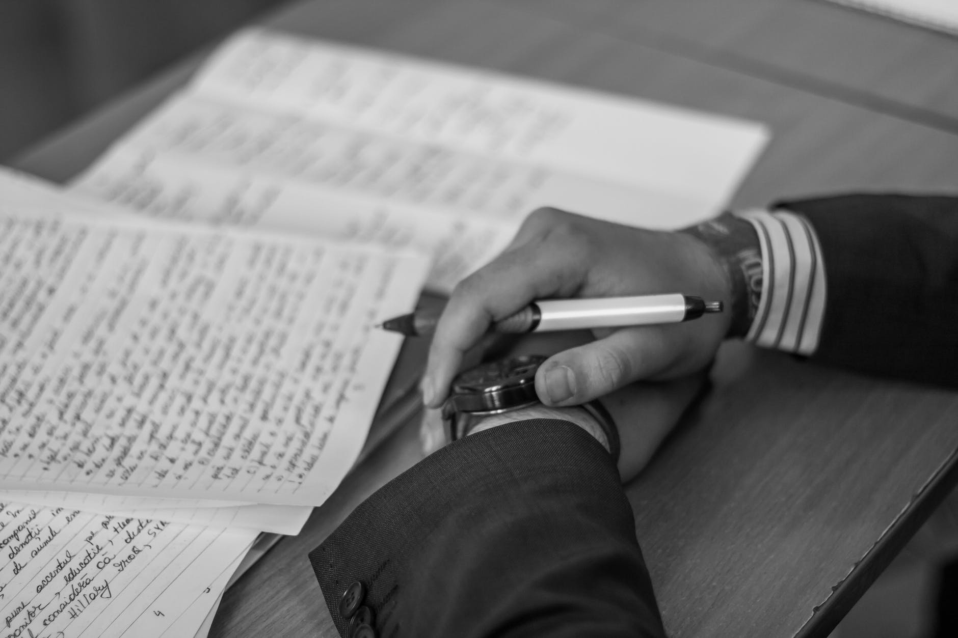 Grayscale photograph of person writing. Writing is a form of research.