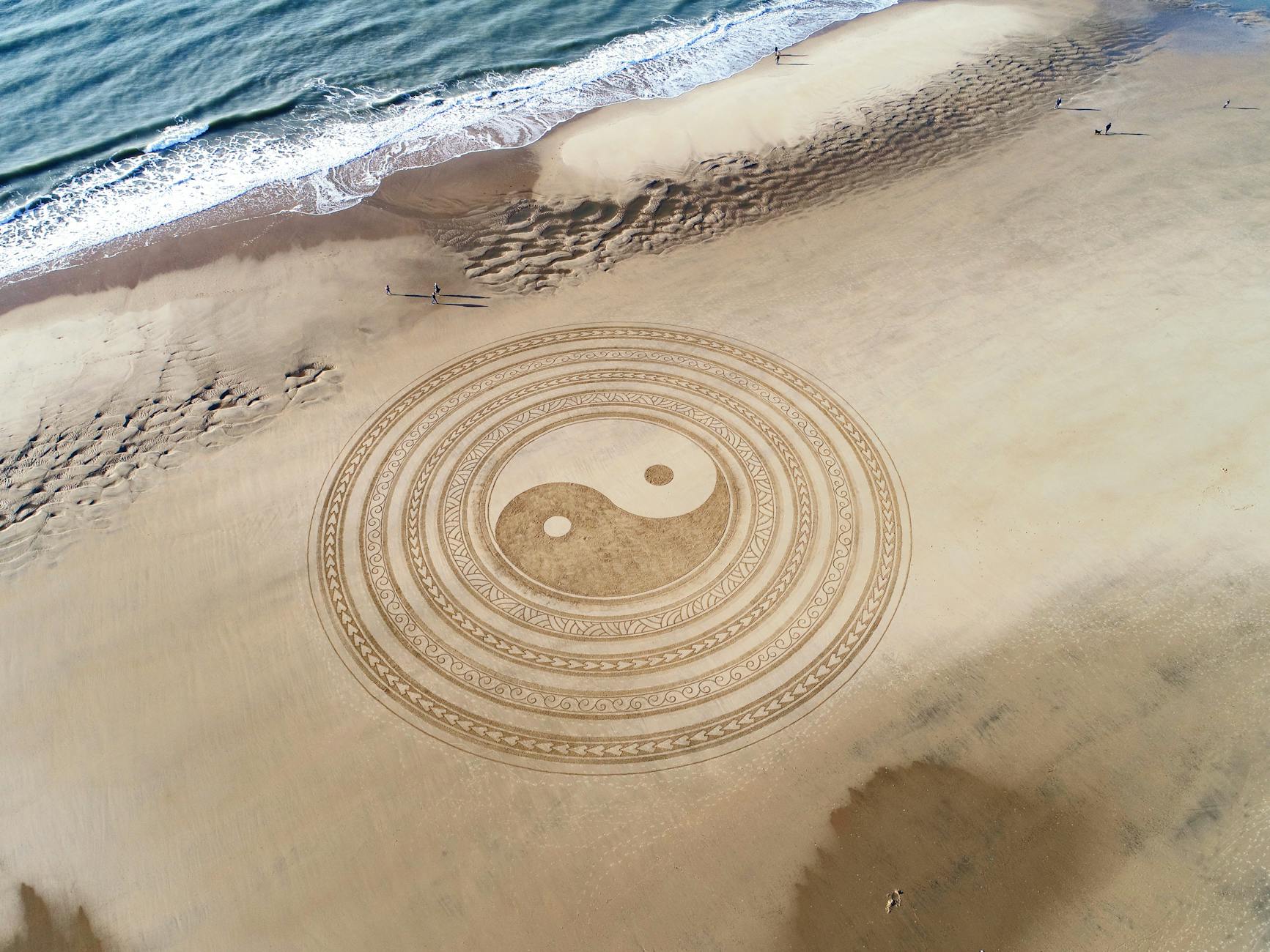 Yin yang symbol on brown beach sand; character and plot are the yin and yang of story