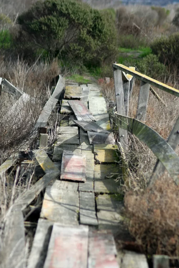 A broken wooden bridge covered in planks.