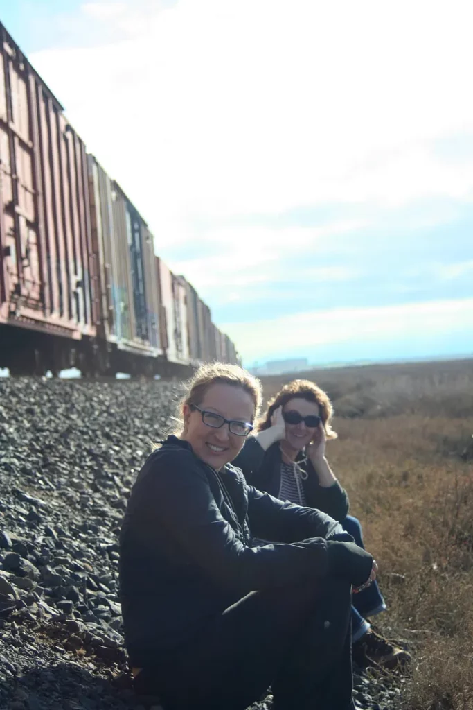 Two women cover their ears at the sound of a passing freight train.