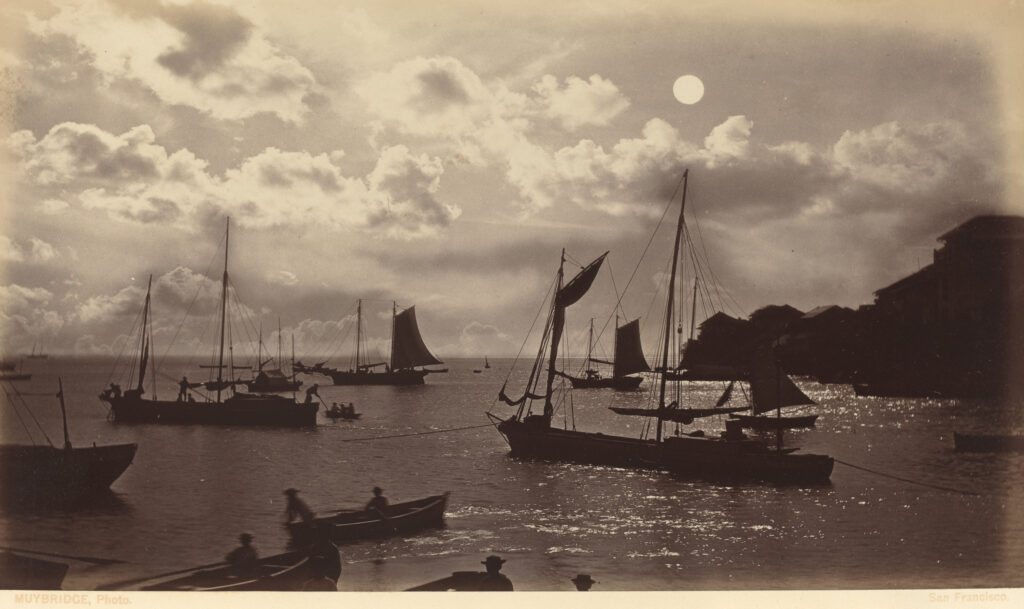 Boats and small fishing ships under the full moon.
