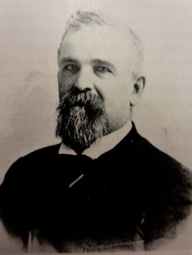 A man in his forties or fifties, well-dressed, with short gray hair and a darker, lengthy beard.