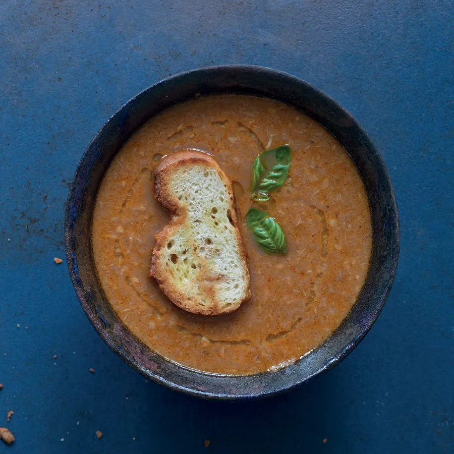 A bowl of fish soup with a crouton floating on top.