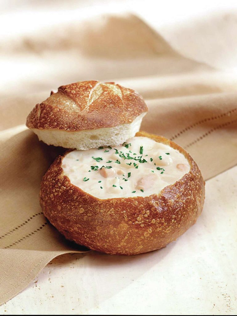 A bowl of clam chowder in a sourdough bread bowl
